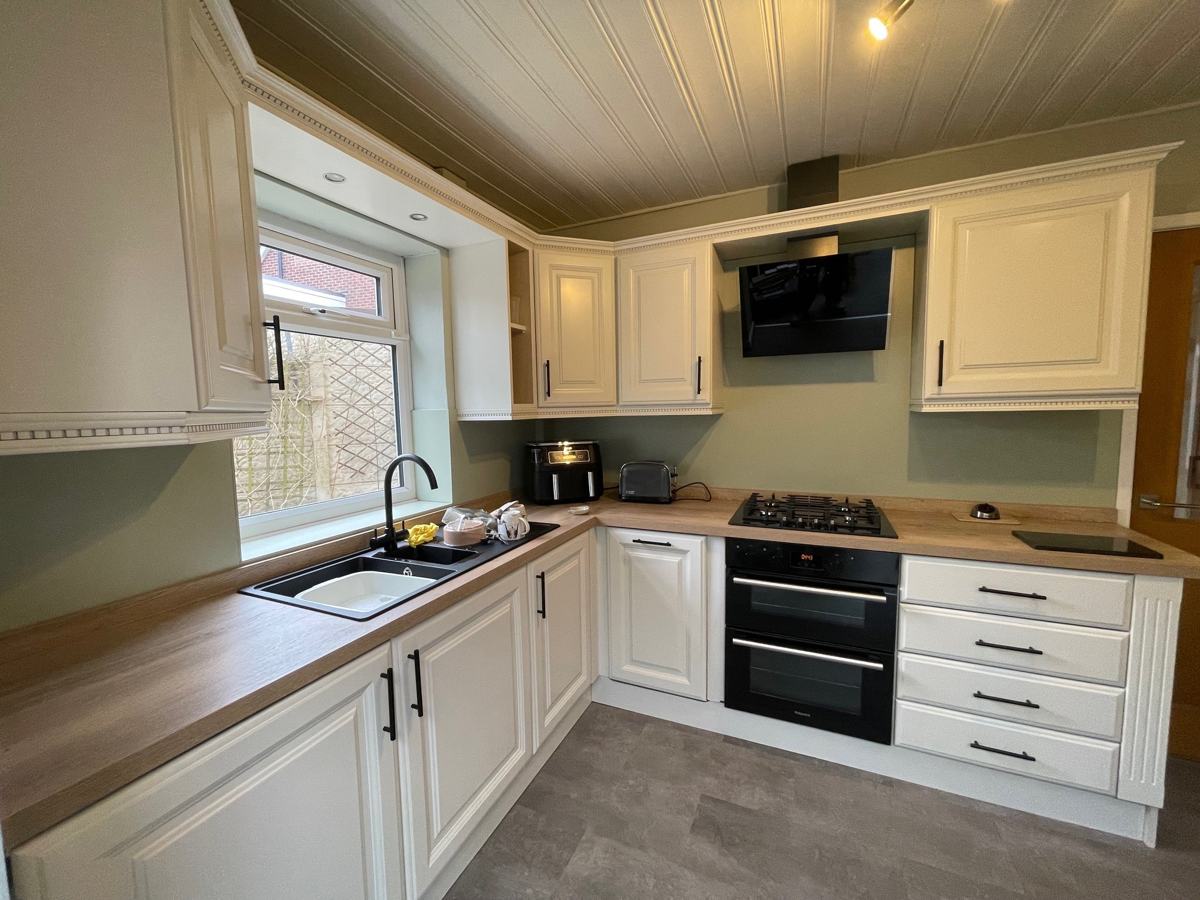 Mossley kitchen after: cream painted units, glass splashback and oak-effect worktops