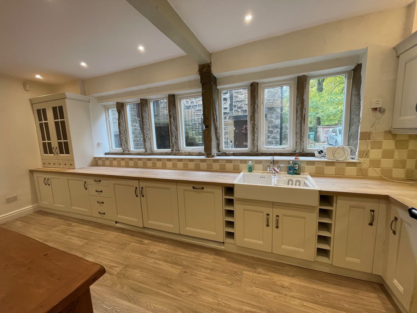 The same kitchen after: units painted soft cream with a light wood-effect floor