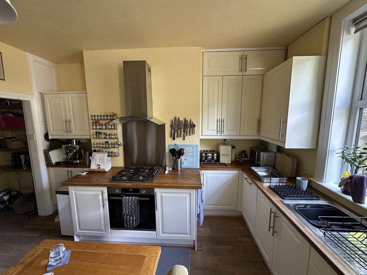 Cooker wall before: cream units, wooden worktops and steel splashback