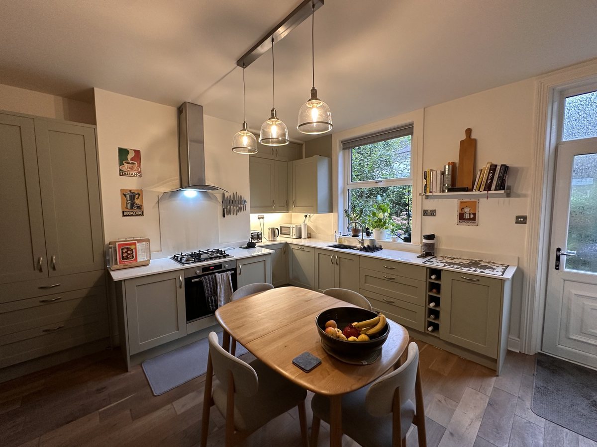 Sink wall after: sage green units and quartz worktops by the window