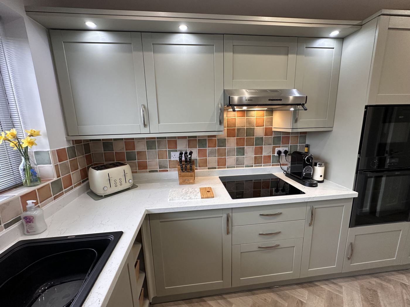 Mossley kitchen after: sage green units, under-cabinet lighting and herringbone floor
